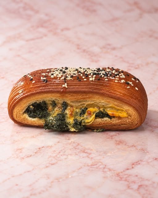 A savoury pastry with spinach on pink marble